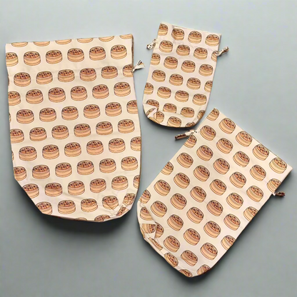 Three sizes of reusable cotton gift bags with illustrated dim sum basket print.