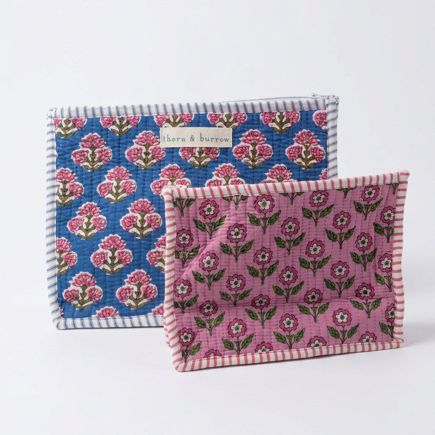 Two woven fabric pouches with floral prints, one in blue and one in pink, both with striped borders, displayed on a clean white background.