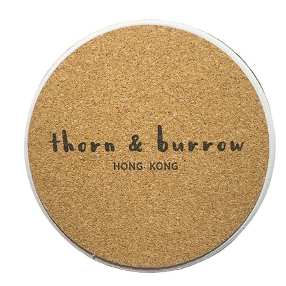 Reverse of a Thorn & Burrow ceramic coaster showing the cork backing and logo